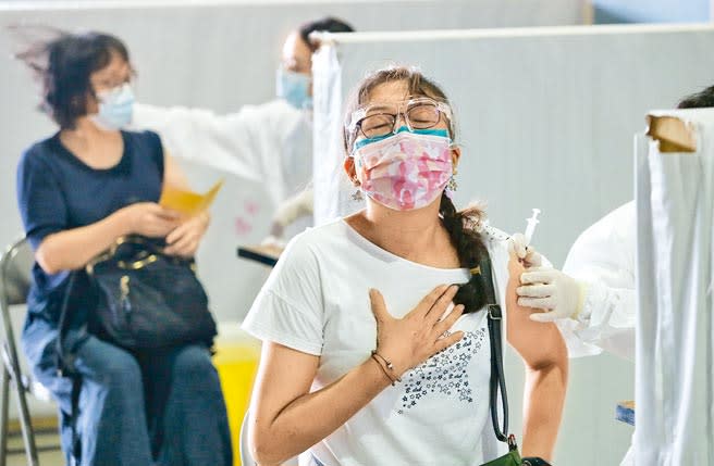 台北市首波校園教職員工疫苗開打，14日在網球中心接種站有教職員注射時，手輕撫胸口深呼吸放鬆全身。（王英豪攝）