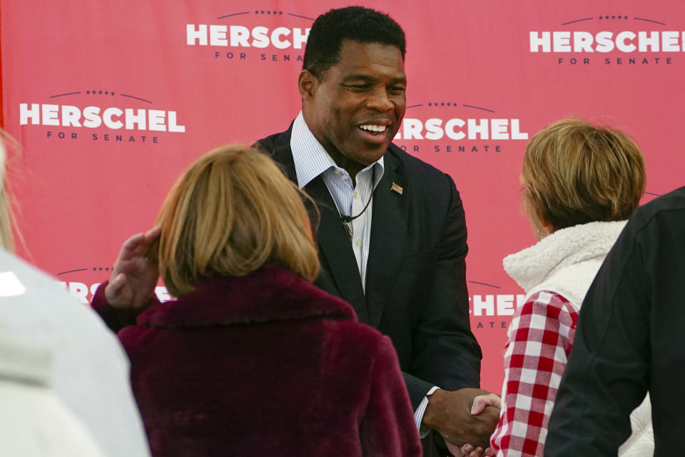 FILE - Herschel Walker, Republican candidate for U.S. Senate in Georgia, greets supporters during a campaign rally Oct. 18, 2022, in Atlanta. Walker campaigns for the U.S. Senate as a champion of free enterprise and advocate for the mentally ill, felons and others. And the Georgia Republican has called for policies that blend those priorities. Yet Walker, through a major chicken processor that he touts as a principal partner to one of his primary businesses, has benefited from years of unpaid labor by drug offenders routed to the facility by Oklahoma state courts. (AP Photo/John Bazemore, File)