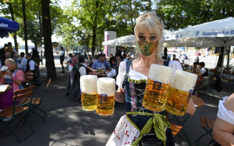 A server carries mugs during a barrel tapping at a beer garden near Theresienwiese where Oktoberfest would have started today - REUTERS