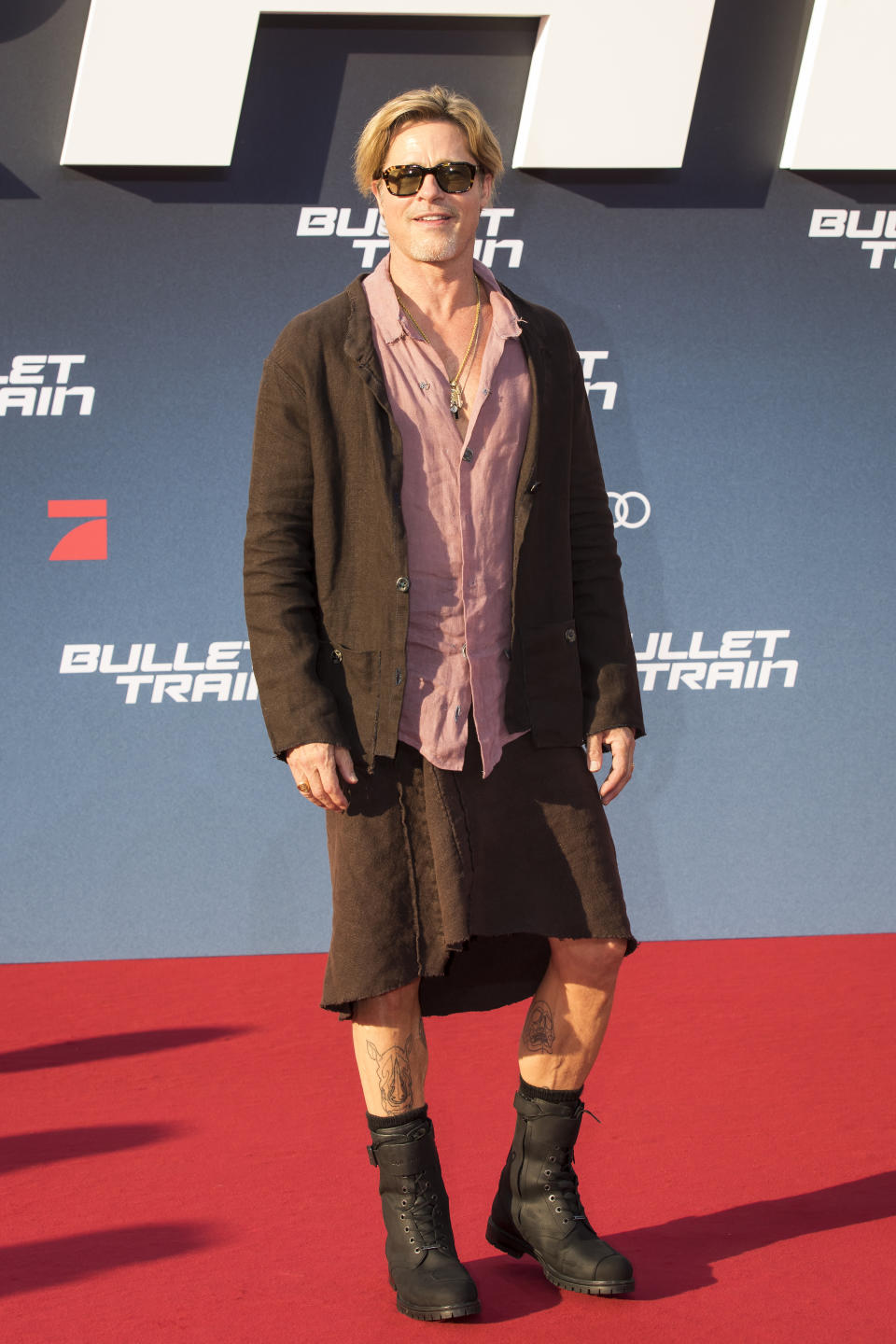 Brad Pitt wears a brown linen skirt and jacket with combat boots on the red carpet. (Getty Images)