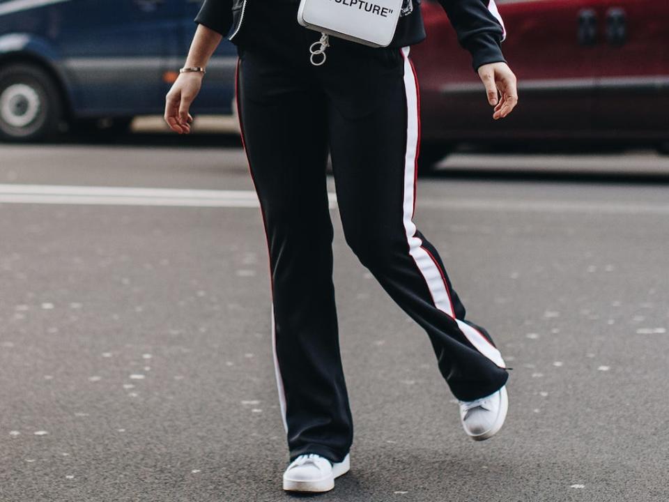 woman crossing the street wearing a track suit and white sneakers