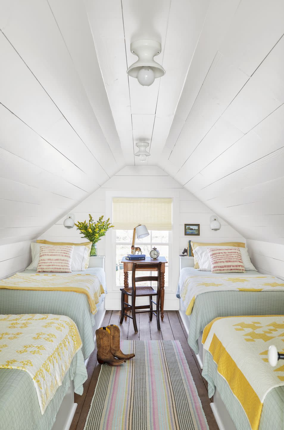 white attic bedroom with four twin beds with yellow and white quilts