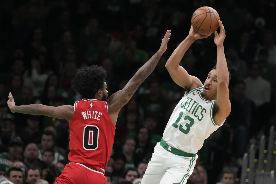 Boston Celtics guard Malcolm Brogdon (13) passes the ball while pressured by Chicago Bulls guard Coby White (0) during the first half of an NBA basketball game, Monday, Jan. 9, 2023, in Boston. (AP Photo/Charles Krupa)