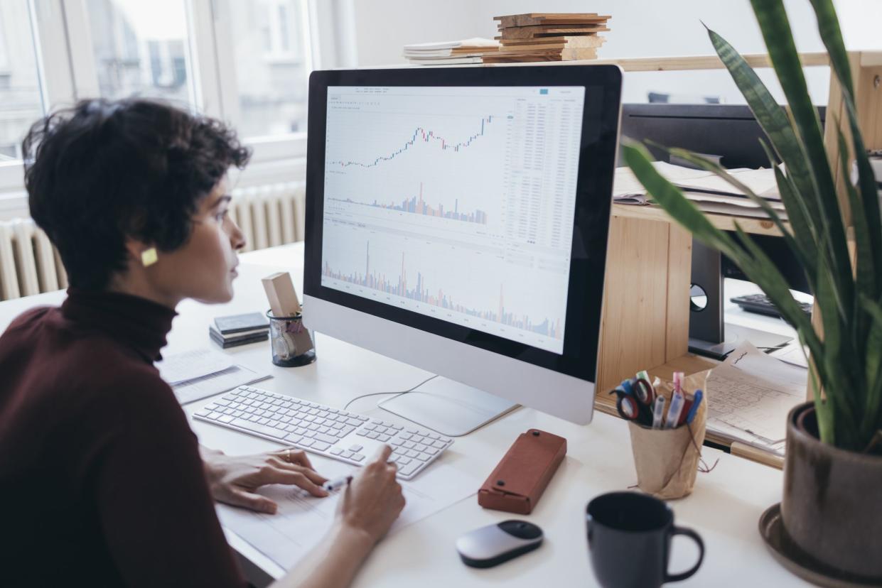 A beautiful female marketing expert looking at the screen of a computer and collecting information from the graphs and charts displayed.