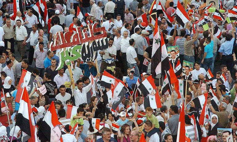 Thousands of pro-regime Syrians wave their national flag and portraits of President Bashar al-Assad during a rally in support of "national unity in Damascus on July 8. Syrian security forces use tanks, bullets and tear gas against anti-regime protesters by day, but by night they are more stealthy, targeting dissent using the opposition's own weapon, the Internet