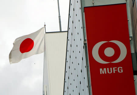 FILE PHOTO - Japan's national flag is seen behind the logo of Mitsubishi UFJ Financial Group Inc (MUFG) at its bank branch in Tokyo, Japan September 5, 2017. REUTERS/Kim Kyung-Hoon