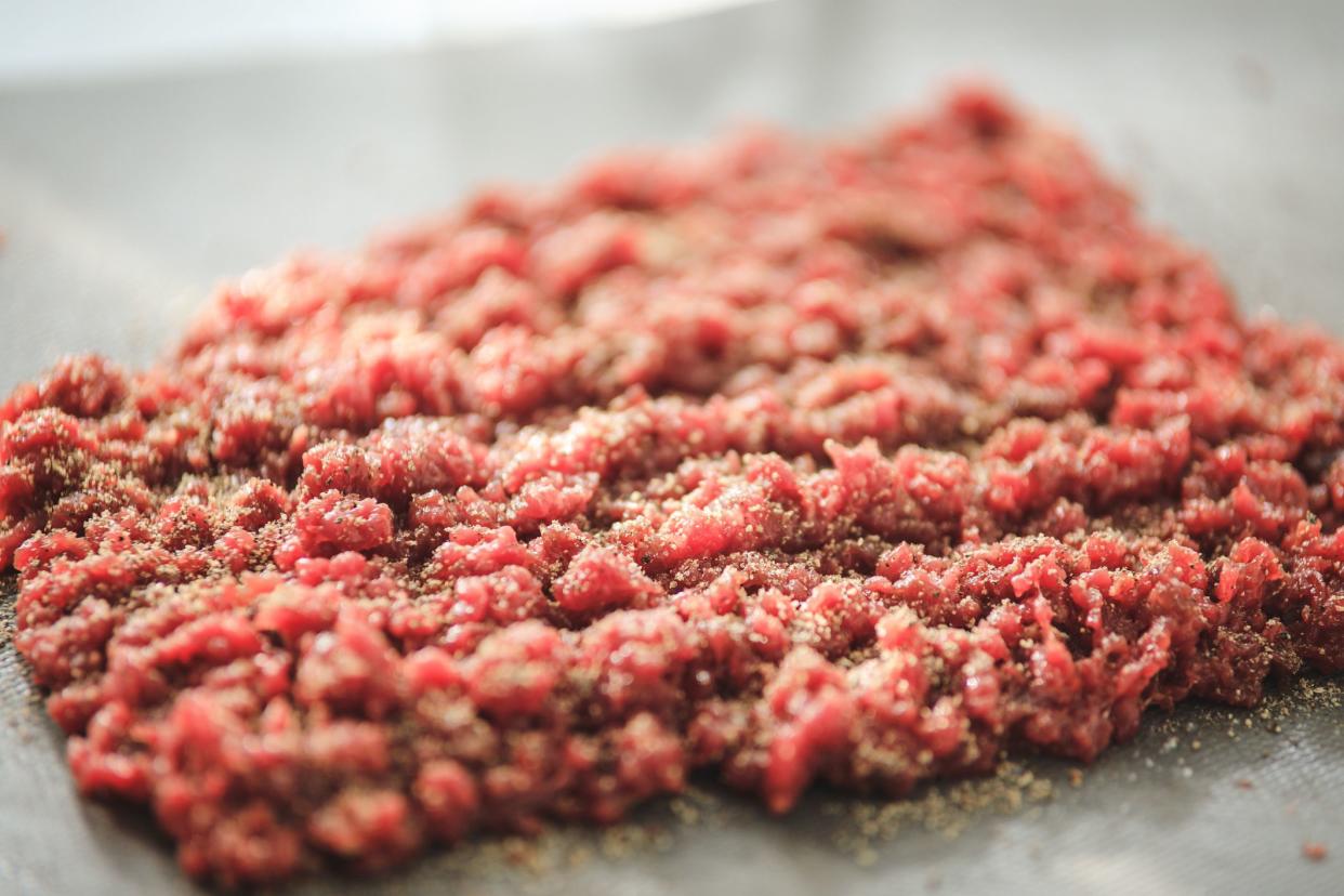 Horsemeat finely chopped, seasoned with black pepper, preparing steak tartare, or minced steak, close up, selective focus