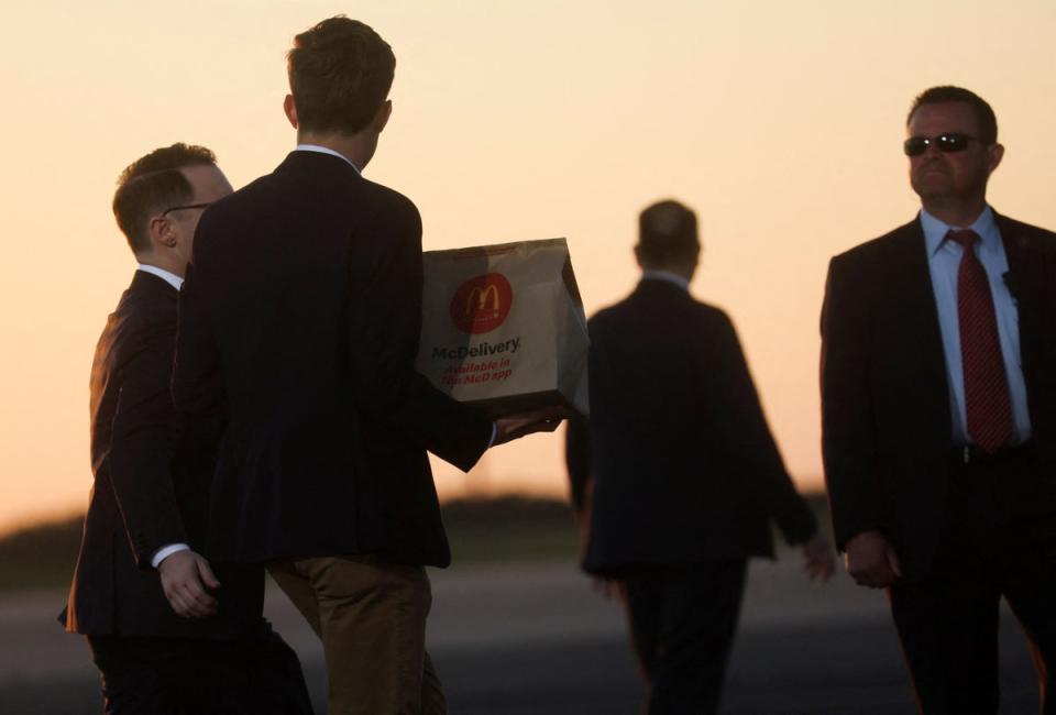 Staff carrying McDonald's on to the former president’s plane after rally (REUTERS)