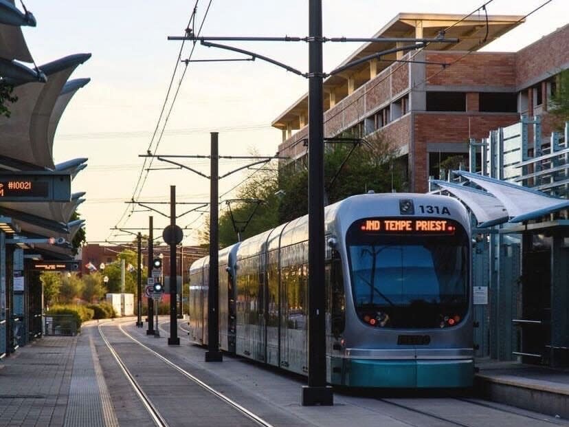 A light rail train stops between buildings at a station