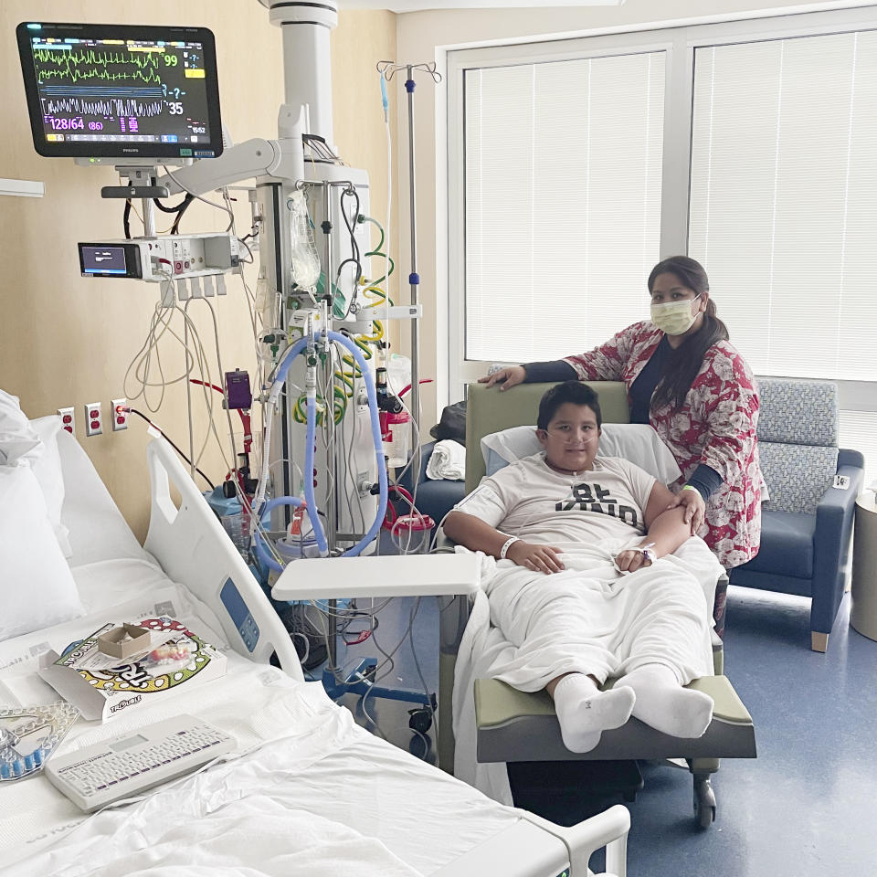 This 2021 photo provided by Children’s Health shows Francisco Rosales, 9, and his mother, Yessica Gonzalez, in the intensive care unit at Children’s Medical Center in Dallas, Texas. The day before he was supposed to start fourth grade, Francisco was admitted to the hospital due to severe COVID-19, struggling to breathe, with dangerously low oxygen levels and an uncertain outcome. (Adriana Lantzy/Children’s Health via AP)