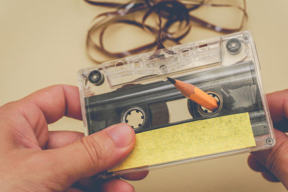 Someone using a pencil to wind a cassette