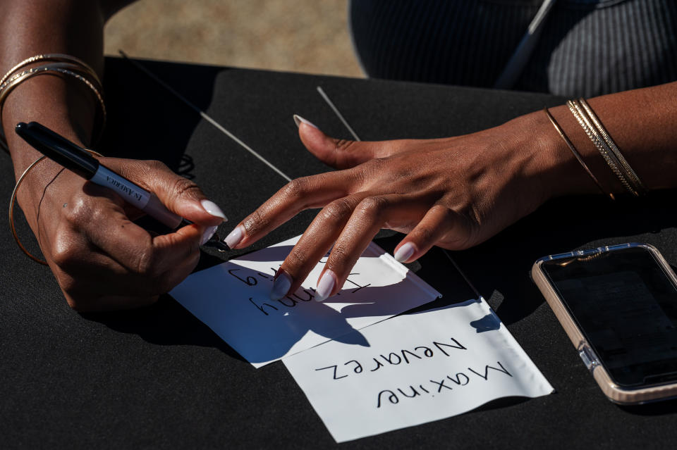 Kaye Williams writes names on two flags for “In America: Remember.” (Craig Hudson for The Washington Post)