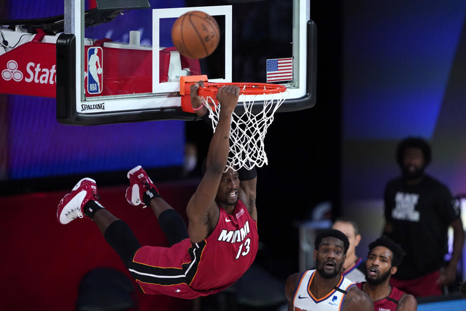 Bam Adebayo (13) del Heat de Miami se cuelga del aro sobre Deandre Ayton de los Suns de Phoenix, el sábado 8 de agosto de 2020. (AP Foto/Ashley Landis, Pool)