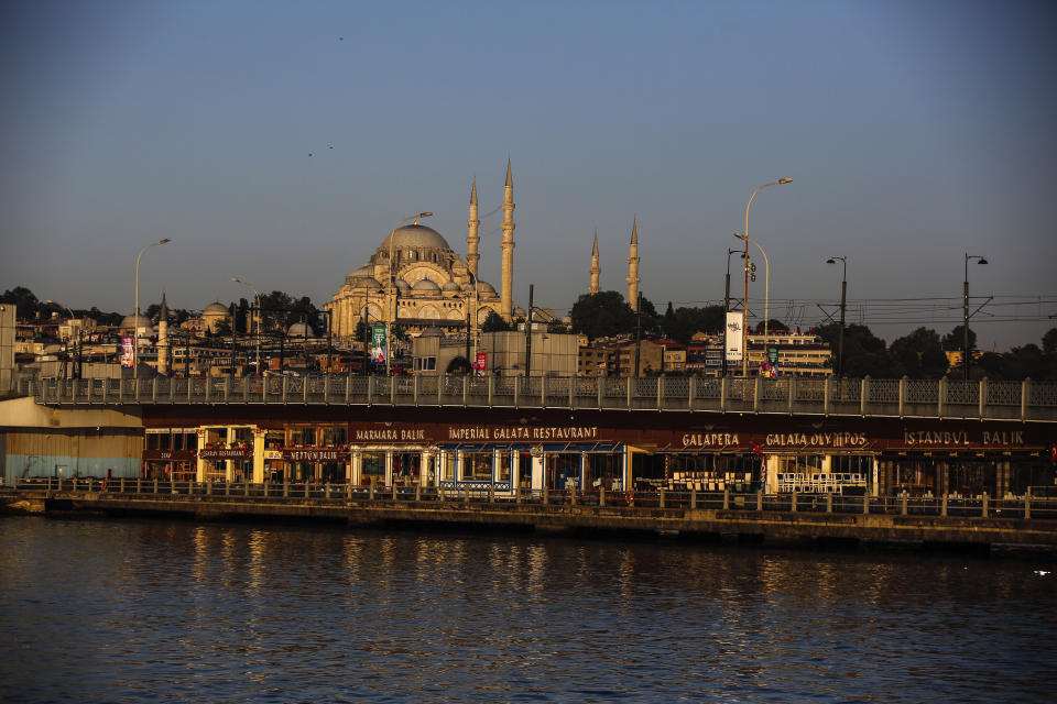 The historical Suleymaniye Mosque where only few face masked people allowed to offer the Eid al-Fitr prayer amid concerns of the coronavirus outbreak, is seen from Golden Horn, in Istanbul, early Sunday, May 24, 2020. Muslims in the world are marking a muted and gloomy religious festival of Eid al-Fitr, the end of the fasting month of Ramadan - a usually joyous three-day celebration that has been significantly toned down due to the new coronavirus outbreak.(AP Photo/Emrah Gurel)