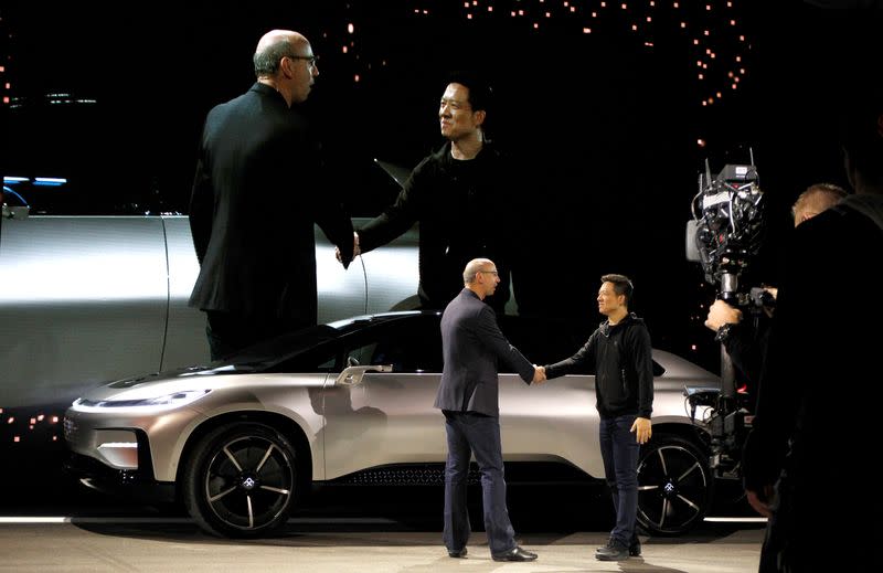 Nick Sampson (L), senior vice president of product R&D and engineering at Faraday Future, shakes hands with YT Jia (L), founder and CEO of LeEco, in front of a Faraday Future FF 91 electric car during an unveiling event in Las Vegas