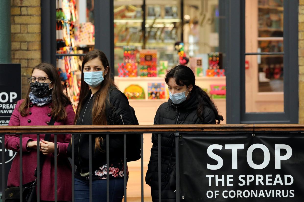 People wearing protective face masks look over balcony in Covent Garden as coronavirus cases rise by more than 26,000 in the UK: REUTERS