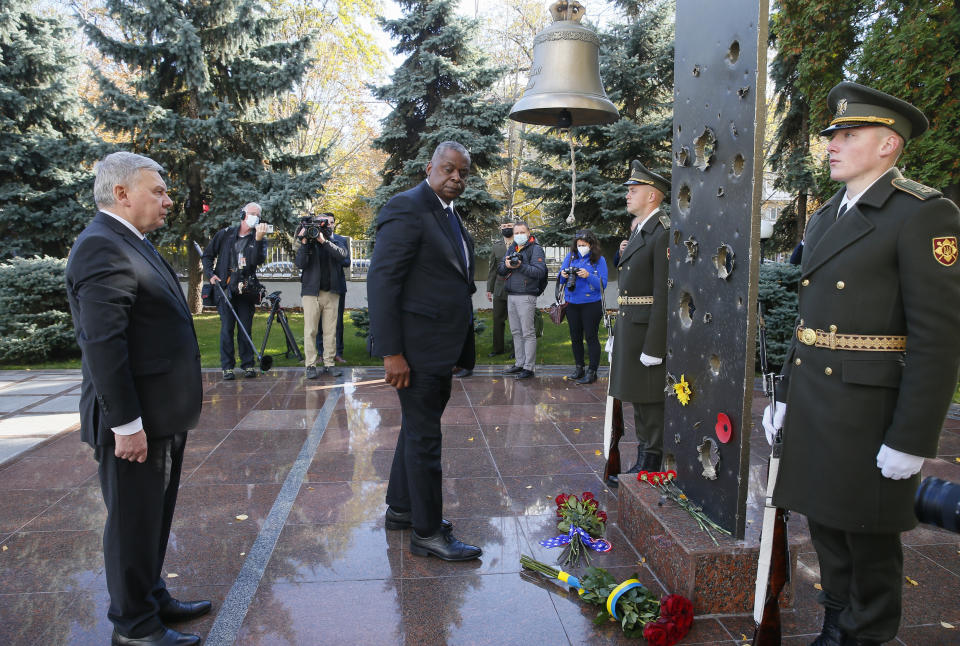 Ukrainian Defense Minister Andriy Taran, left, and U.S. Defense Secretary Lloyd Austin lay flowers on a monument commemorating fallen defenders in Kyiv, Ukraine, Tuesday, Oct. 19, 2021. (Gleb Garanich/Pool Photo via AP)