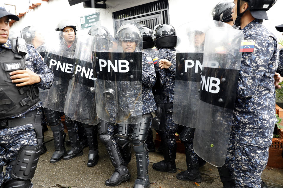 Members of Venezuela's National Police rush in to secure Bolivia’s Embassy after learning that opposition politician Juan Guaido and supporters were marching to the embassy to show their support for Bolivia’s interim government, in Caracas, Venezuela, Saturday, Nov. 16, 2019. President Nicolas Maduro’s socialist party also called its members to demonstrate in solidarity with Bolivia’s Evo Morales, who resigned the presidency and fled into exile in Mexico on Nov. 10, claiming a coup d’etat following massive protests accusing him of engineering a fraudulent reelection. (AP Photo/Ariana Cubillos)