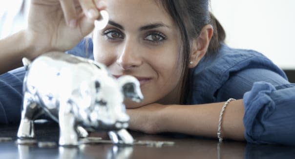 Woman putting coin into piggy bank