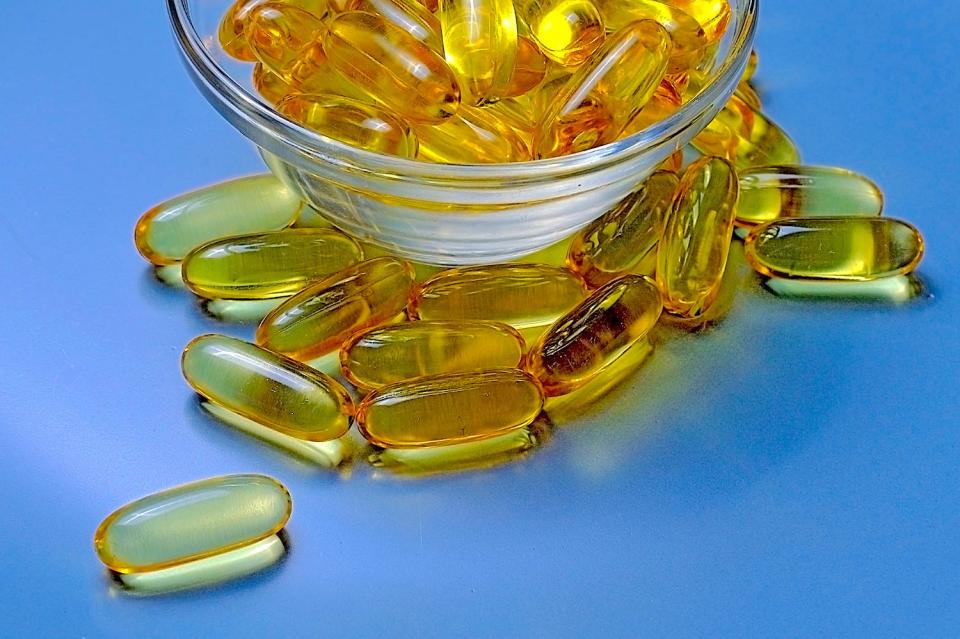 Yellow capsules spilling out of a glass bowl.