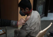 A health worker administers Covid-19 vaccination to a boy, in New Delhi, India, Friday, Jan. 28, 2022. Indian health officials said that the first signs of COVID-19 infections plateauing in some parts of the vast country were being seen, but cautioned that cases were still surging in some states. (AP Photo/Manish Swarup)