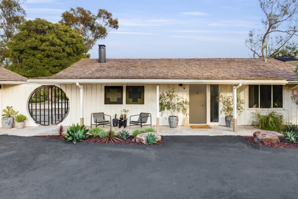 She kept the exterior mostly as is, but updated it with white paint and a black accent for the unusual round gate. A green front door matches the shade found inside.