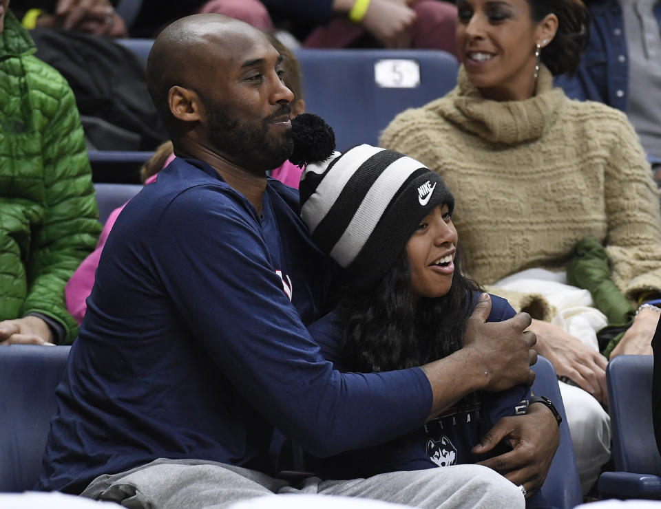 FILE - In this March 2, 2019, file photo Kobe Bryant and his daughter Gianna watch the first half of an NCAA college basketball game between Connecticut and Houston in Storrs, Conn. A public memorial service for Bryant, Gianna and seven others killed in a helicopter crash is planned for Monday, Feb. 24, 2020, at Staples Center in Los Angeles, a person with knowledge of the details told The Associated Press on Thursday, Feb. 6, 2020. (AP Photo/Jessica Hill, File)