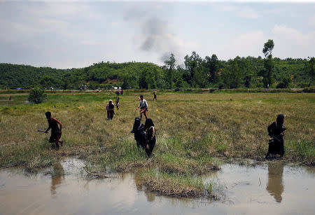 Rohingya people try to come to the Bangladesh side from No Man’s Land as smoke rises after a gunshot was heard on the Myanmar side, in Cox’s Bazar, Bangladesh August 28, 2017. REUTERS/Mohammad Ponir Hossain