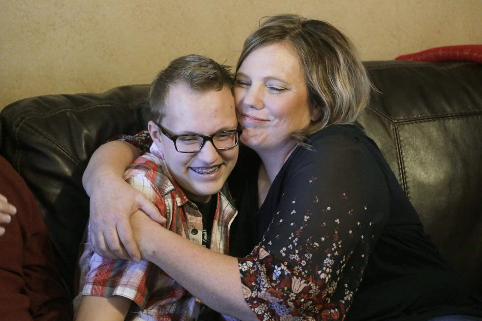 Dex Rumsey, 15, receives a hug from his mother Robyn Friday, Jan. 17, 2020, in Roy, Utah. Dex Rumsey, 15, of Roy, Utah, came out as transgender at age 12. In consultation with a counselor and doctors, he gradually began wearing short hair and boy's clothes, then began using puberty blockers and eventually testosterone. His parents say he's gone from a shy, withdrawn child to a happy, thriving kid. He scared he could become depressed and suicidal again a ban on hormone therapy and sex-reassignment surgery for minors were to pass. (AP Photo/Rick Bowmer)