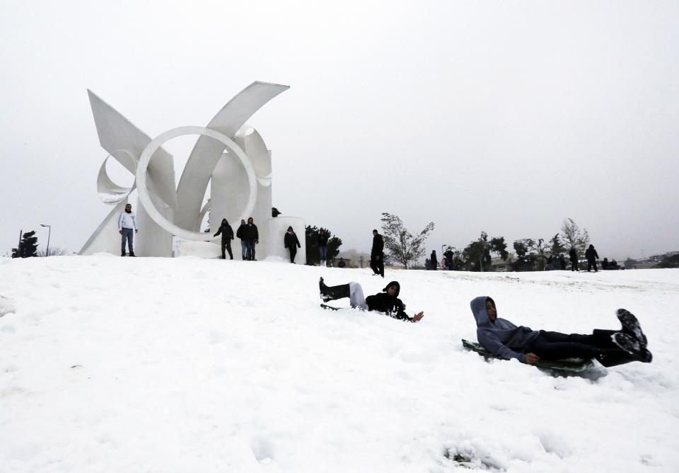 People play in the snow following a snowstorm at a park in Jerusalem December 14, 2013. Jerusalem's heaviest snow for 50 years forced Israeli authorities to lift a Jewish sabbath public transport ban on Saturday and allow trains out of the city where highways were shut to traffic. REUTERS/ Ammar Awad (JERUSALEM - Tags: ENVIRONMENT)