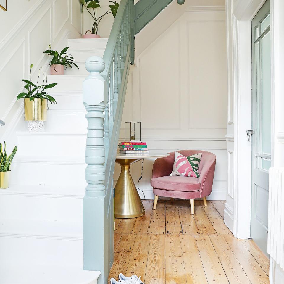 velvet armchair and brass table with blue bannister and white stairs