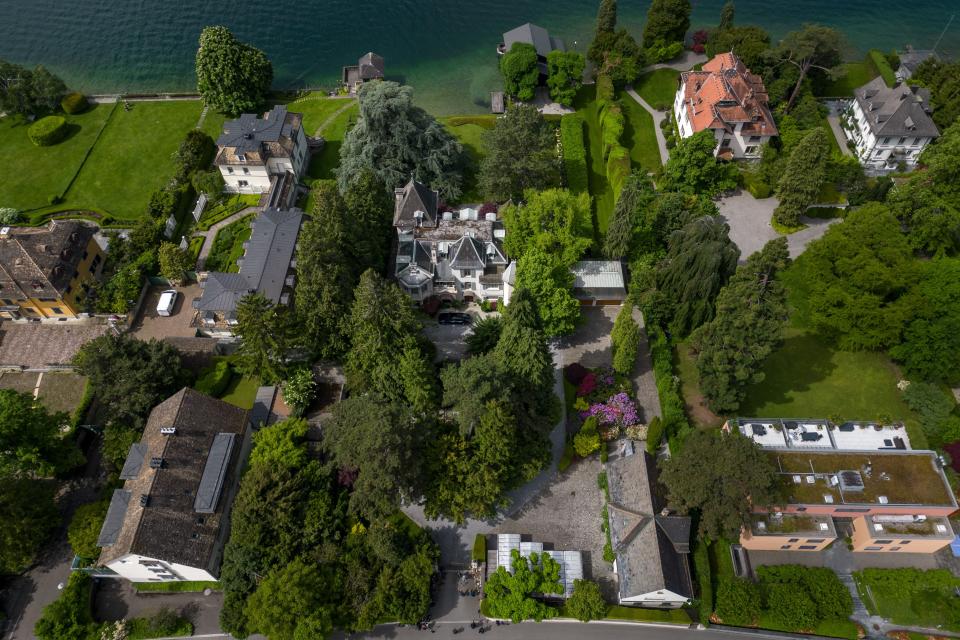 An aerial photograph of a large estate on the edge of a lake with several buildings surrounded by trees.