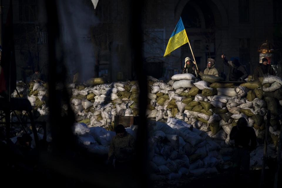 An opposition supporter holds a Ukrainian flag behind a barricade near Kiev's Independence Square, the epicenter of the country's current unrest, Ukraine, Friday, Jan. 31, 2014. Ukraine's embattled president Viktor Yanukovych is taking sick leave as the country's political crisis continues without signs of resolution. (AP Photo/Emilio Morenatti)