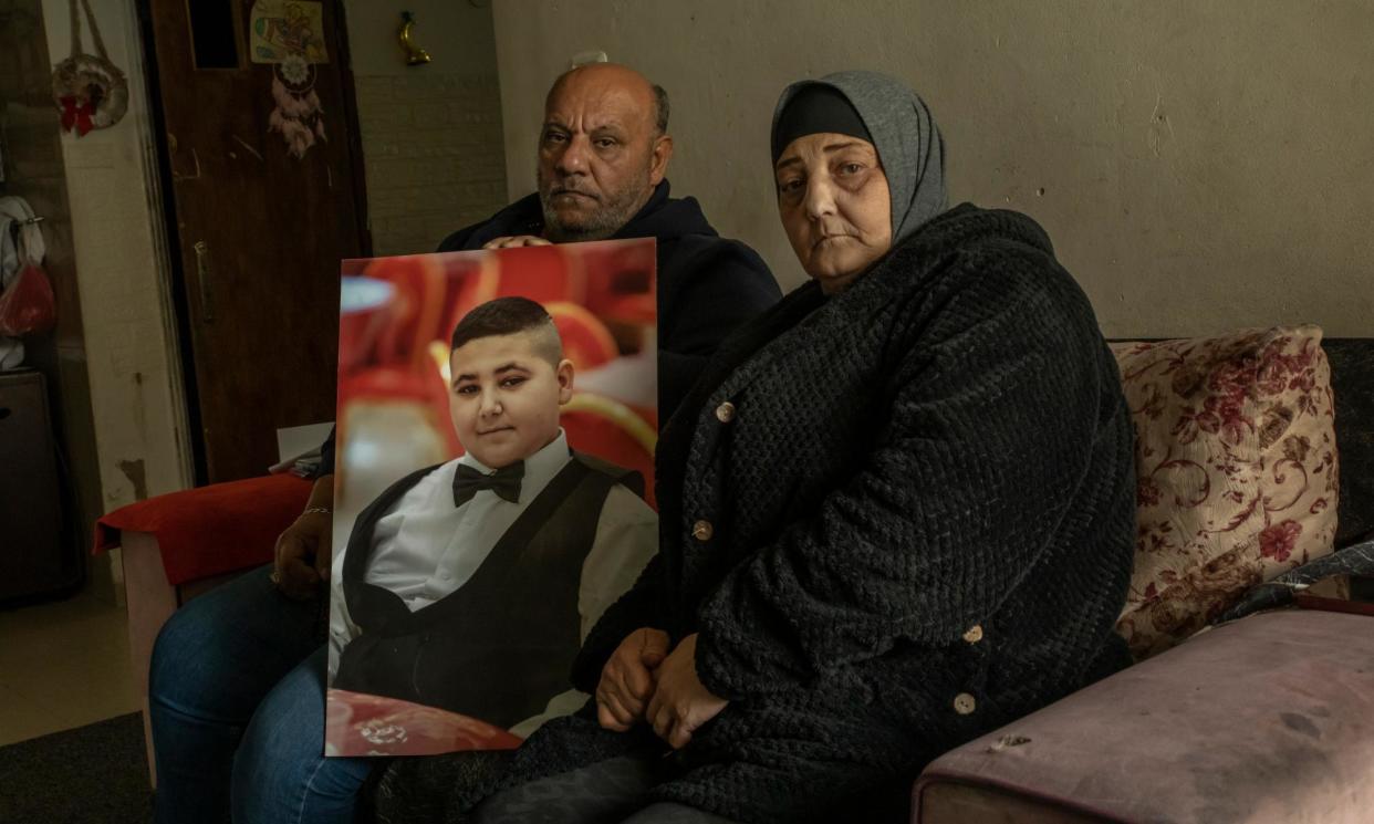 <span>Ali and Rawiya, Rami's parents, in their house in Shuafat refugee camp, hold a photo of their son Rami.</span><span>Photograph: Alessio Mamo/The Guardian</span>