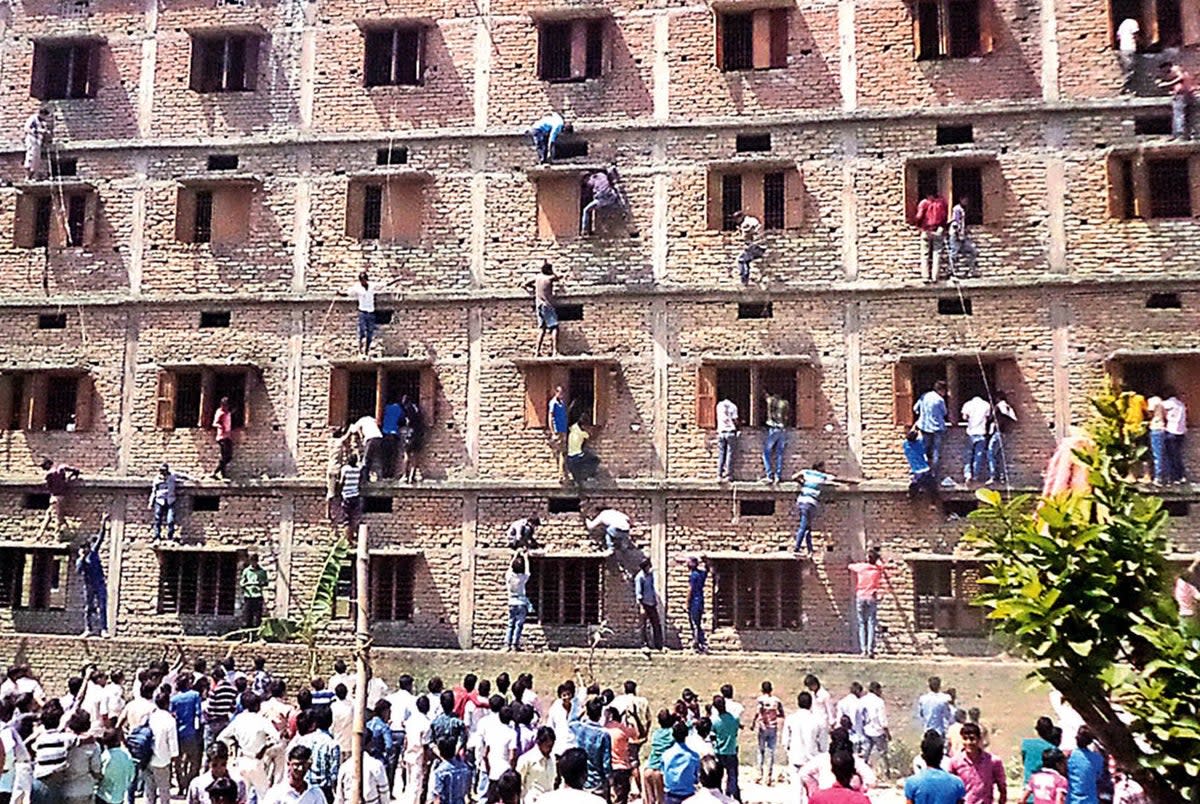 In this photograph taken on 19 March 2015, Indian relatives of students taking school exams climb the walls of the exam building to help pass candidates answers to questions in Vaishali in Bihar (AFP via Getty Images)