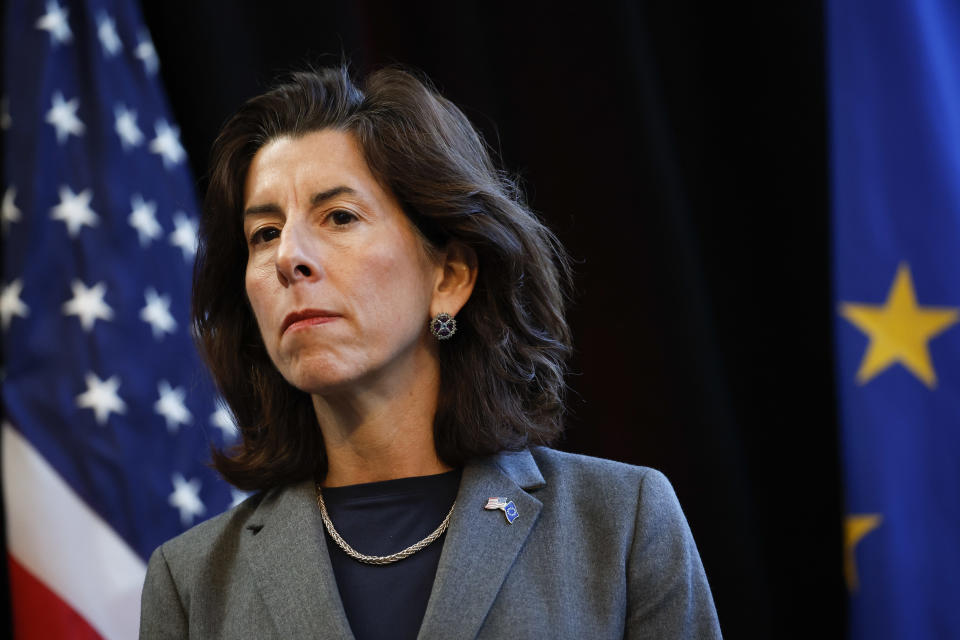 Gina Raimondo against a backdrop of American flags.