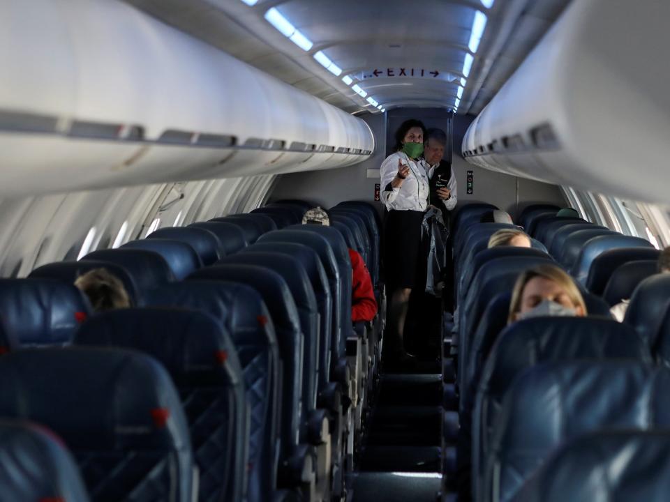 Two flight attendants talk in a nearly empty cabin on a Delta Airlines flight