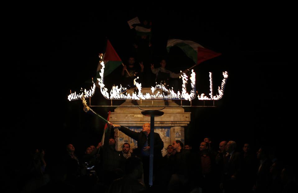 A Palestinian uses a torch to light a sign during a protest against the blockade on Gaza in Gaza City