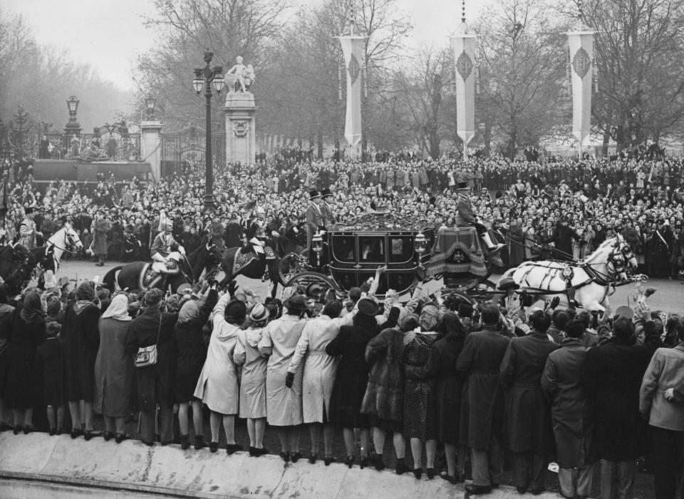 FILE - The Irish Coach, transporting the bride, Britain's Princess Elizabeth and her father, King George VI, to Westminster Abbey, London, Nov. 20, 1947, passes the Victoria Memorial. Decorative banners and bunting line the processional route. Queen Elizabeth II will mark 70 years on the throne Sunday, Feb. 6, 2022 an unprecedented reign that has made her a symbol of stability as the United Kingdom navigated an age of uncertainty. (AP Photo, File)