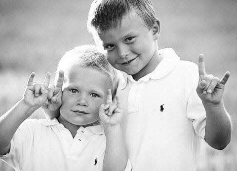 Sam and Jake Ehlinger do the Hook Em Horns sign as kids