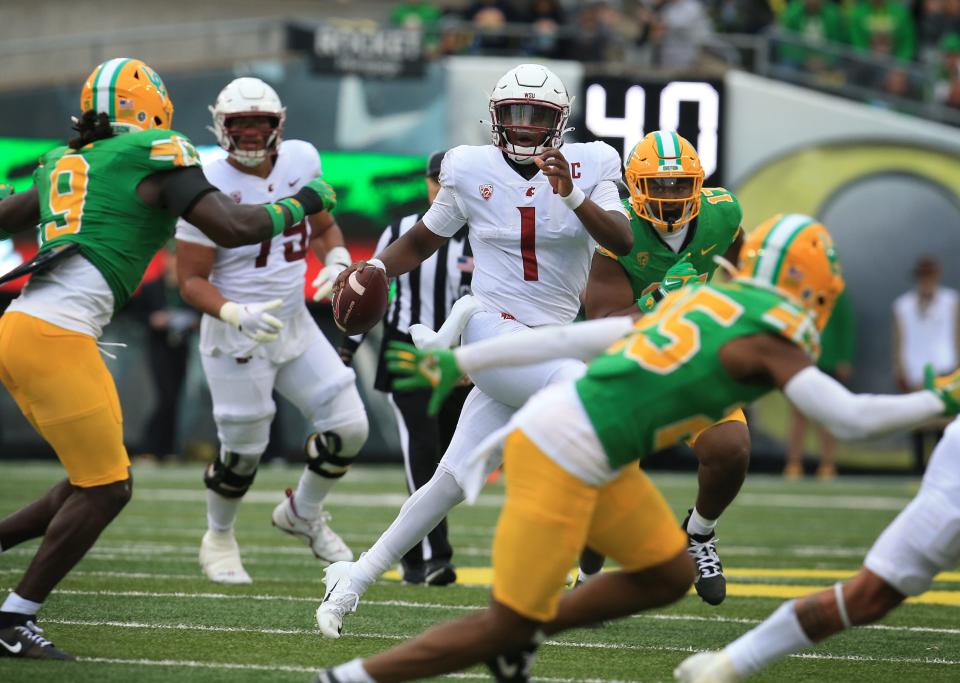 Washington State quarterback Cameron Ward, center, scrambles under pressure from the Oregon defense during the third quarter at Autzen Stadium Saturday, Oct. 21, 2023.