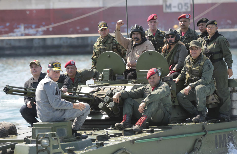 In this photo released to the media by Miraflores presidential palace press office, Venezuelan President Nicolas Maduro raises his fist from an amphibious tank as he poses for photos alongside first lady Cilia Flores and Defense Minister Vladimir Padrino Lopez, center right, at the Naval base in Puerto Cabello, Venezuela, Sunday, Jan. 27, 2019. Opposition lawmaker Juan Guaido has declared himself Venezuela's legitimate leader, as embattled socialist Maduro holds the reins of power. (Marcelo Garcia/Miraflores presidential palace press office via AP)