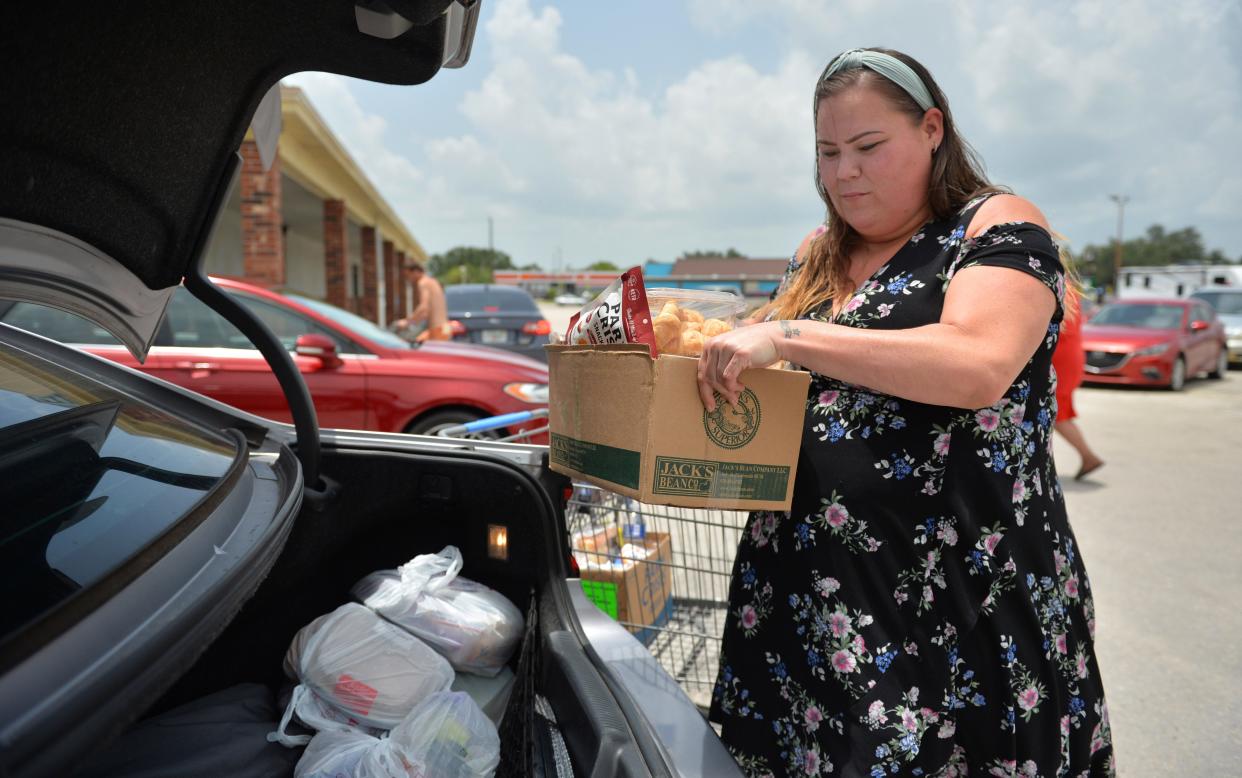 Andrea Guzman-Solano puts groceries in the trunk of her car after stopping by the DeSoto Food and Resource Center in Arcadia.  