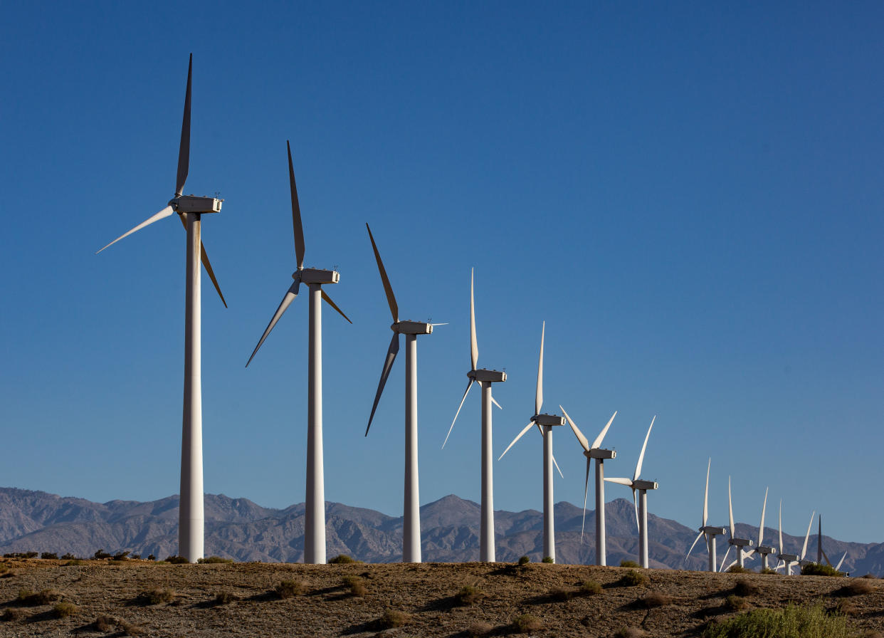 An array of electricity-producing wind turbines can be seen against a backdrop of mountains along Interstate 10 near Palm Springs, Calif.