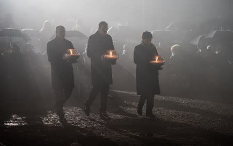 Polish Prime Minister, Mateusz Morawiecki (Centre) lights candles at the International Monument to the Victims of Fascism at Auschwitz-Birkenau on January 27 - Credit:  Anadolu