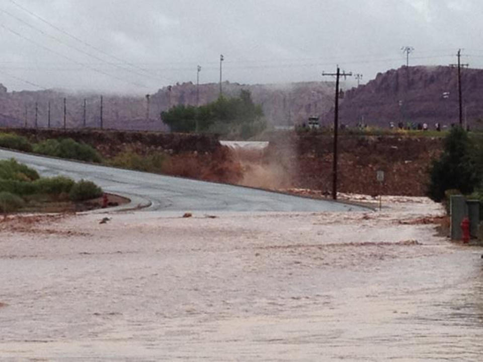 This photo released by the St. George Police Department shows a flooded street after a dike broke and sent floodwaters through the town of Santa Clara, Utah, Tuesday, Sept. 11, 2012. Officials in Santa Clara say they're inspecting whether people can return to about 60 homes and 15 businesses that were evacuated after a dike broke and sent floodwaters through town. City Parks and Recreation Director Brad Hays said a retention pond fed by the Tuacahn Wash filled up after heavy rains Tuesday morning. Authorities ordered homes and businesses below the pond to evacuate about noon, and the dike broke about 45 minutes later. No injuries have been reported from the flooding. (AP Photo/St. George Police Department)