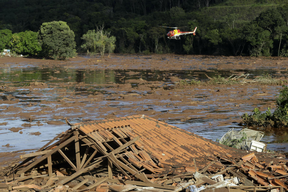 Rescue workers in a helicopter search a flooded area after a dam collapsed in Brumadinho, Brazil, Sunday, Jan. 27, 2019. A massive, deadly river of pale brown mud released by the collapse of a mining company dam on Friday threatens to cause an environmental disaster for Brazil, potentially snatching away livelihoods and driving the spread of disease, activists warned Sunday. (AP Photo/Andre Penner)