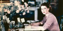 <p>Princess Elizabeth writes a note at her desk in Buckingham Palace.</p>