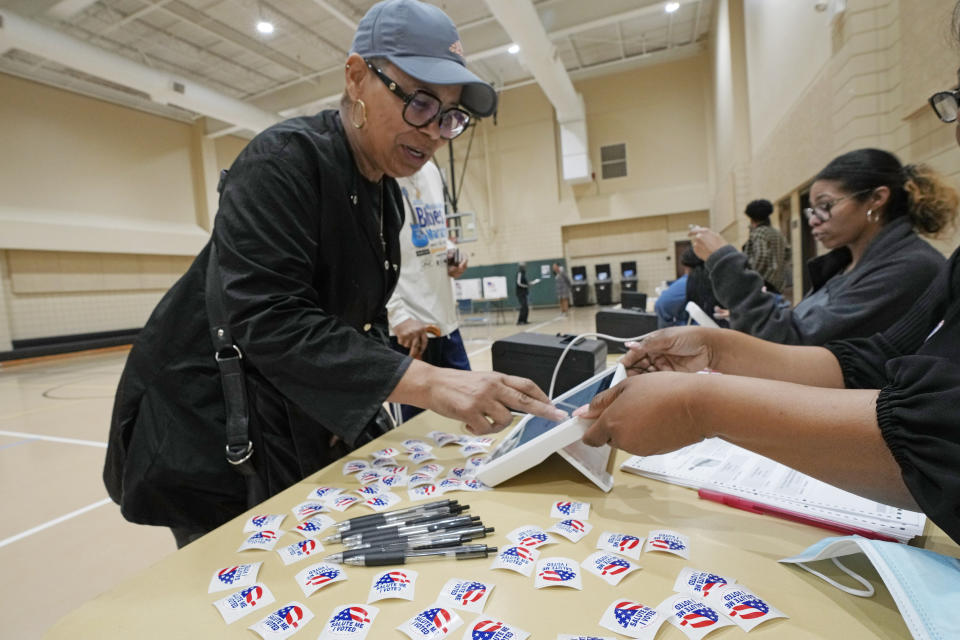 Kathie Washington, 63, left, uses her finger to sign an electronic registry before receiving her paper ballot at a north Jackson, Miss., election precinct, Tuesday, March 12, 2024, as she and others vote in Mississippi's party primaries. Mississippians are voting for all four of the state's U.S. House seats and one U.S. Senate seat. (AP Photo/Rogelio V. Solis)