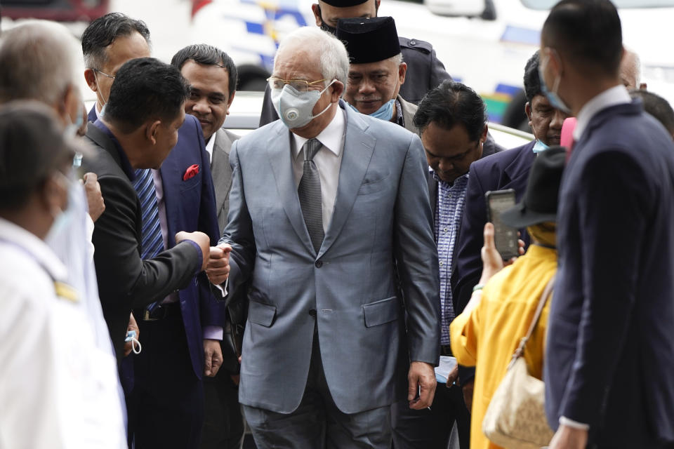 Former Malaysian Prime Minister Najib Razak, center, wearing a face mask greets his supporters upon arrival at court house in Kuala Lumpur, Malaysia, Thursday, June 4, 2020. Closing arguments are expected in the first corruption trial of him linked to the multibillion-dollar looting of the 1MDB state investment fund. (AP Photo/Vincent Thian)